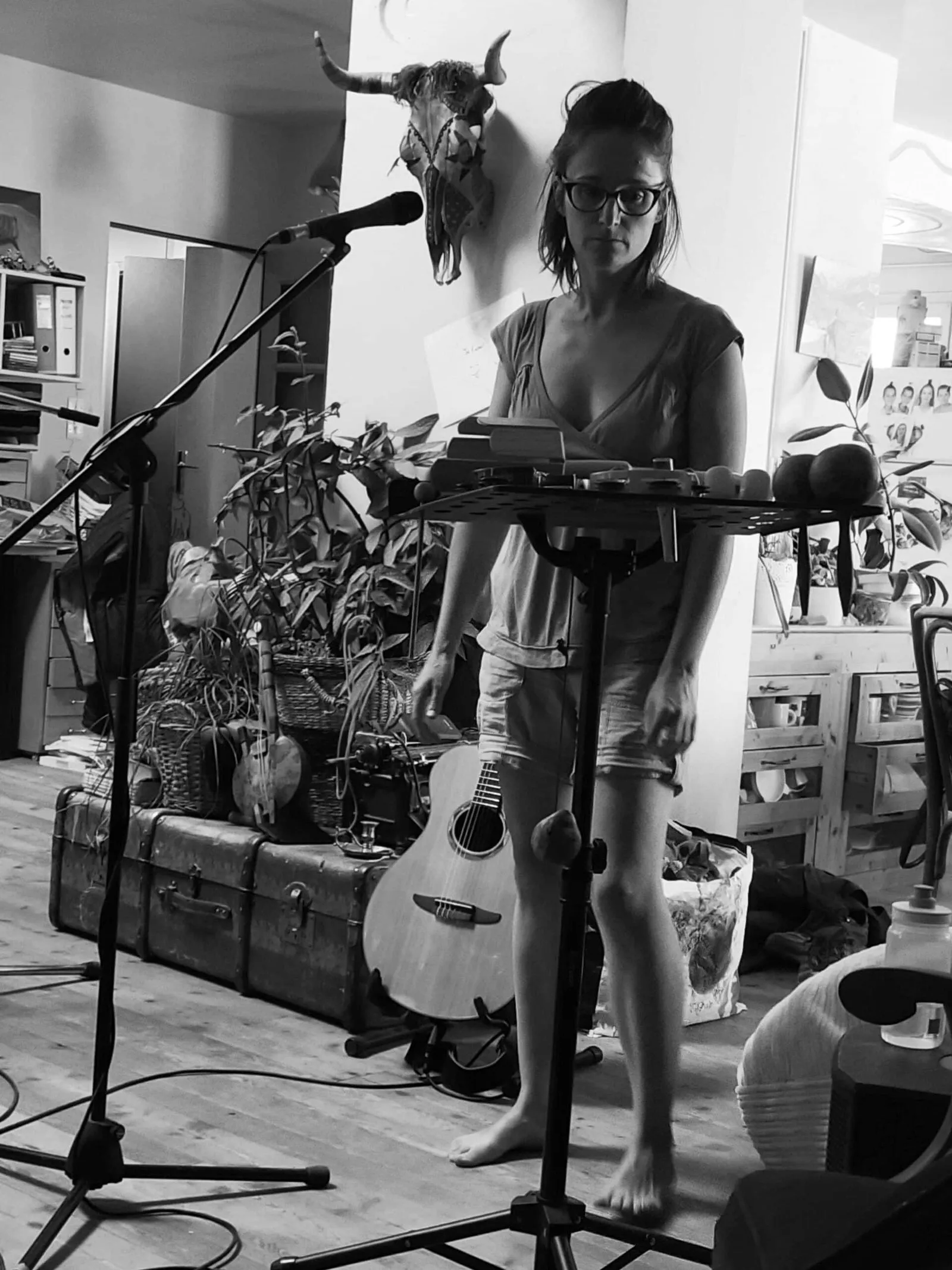 Une musicienne enregistre debout devant un micro, une guitare posée à ses pieds