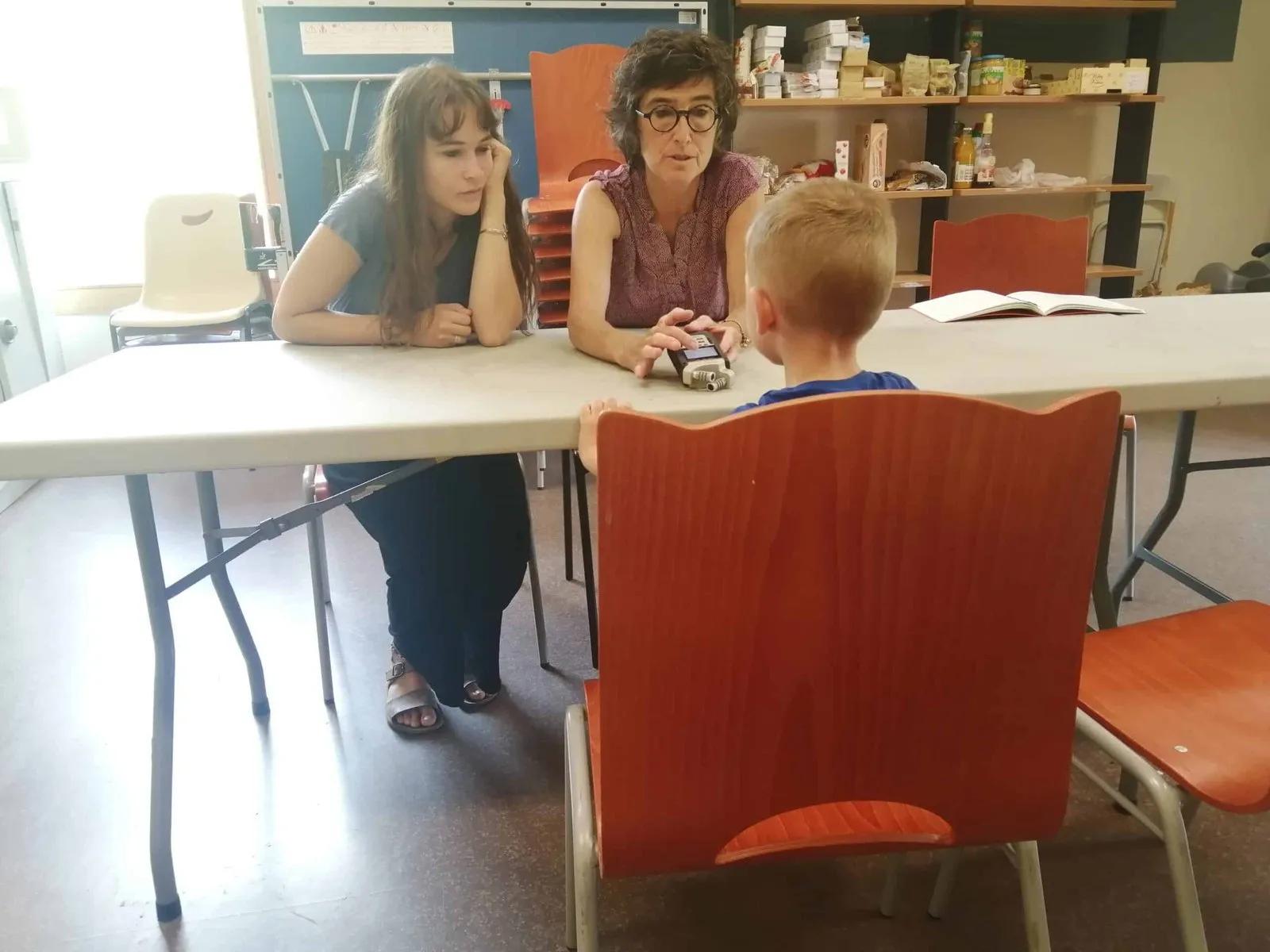 Deux intervenantes échangent avec un enfant autour d’une table