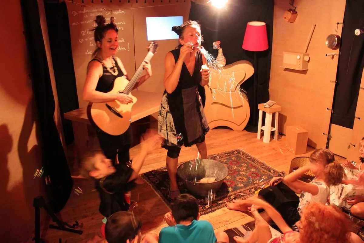 Deux comédiennes, l’une à la guitare, jouent devant les enfants
